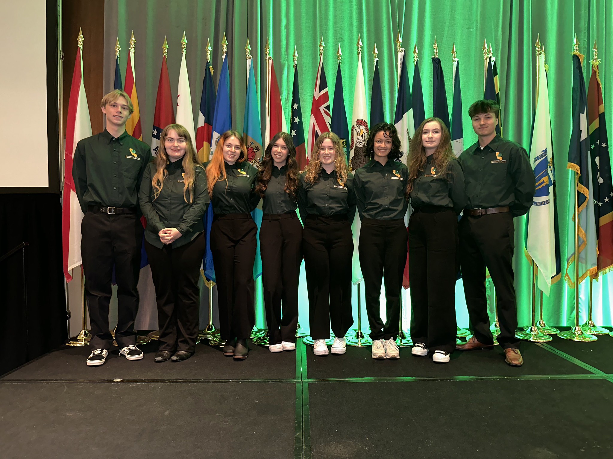 group of youth standing in front of flags with background lighted green