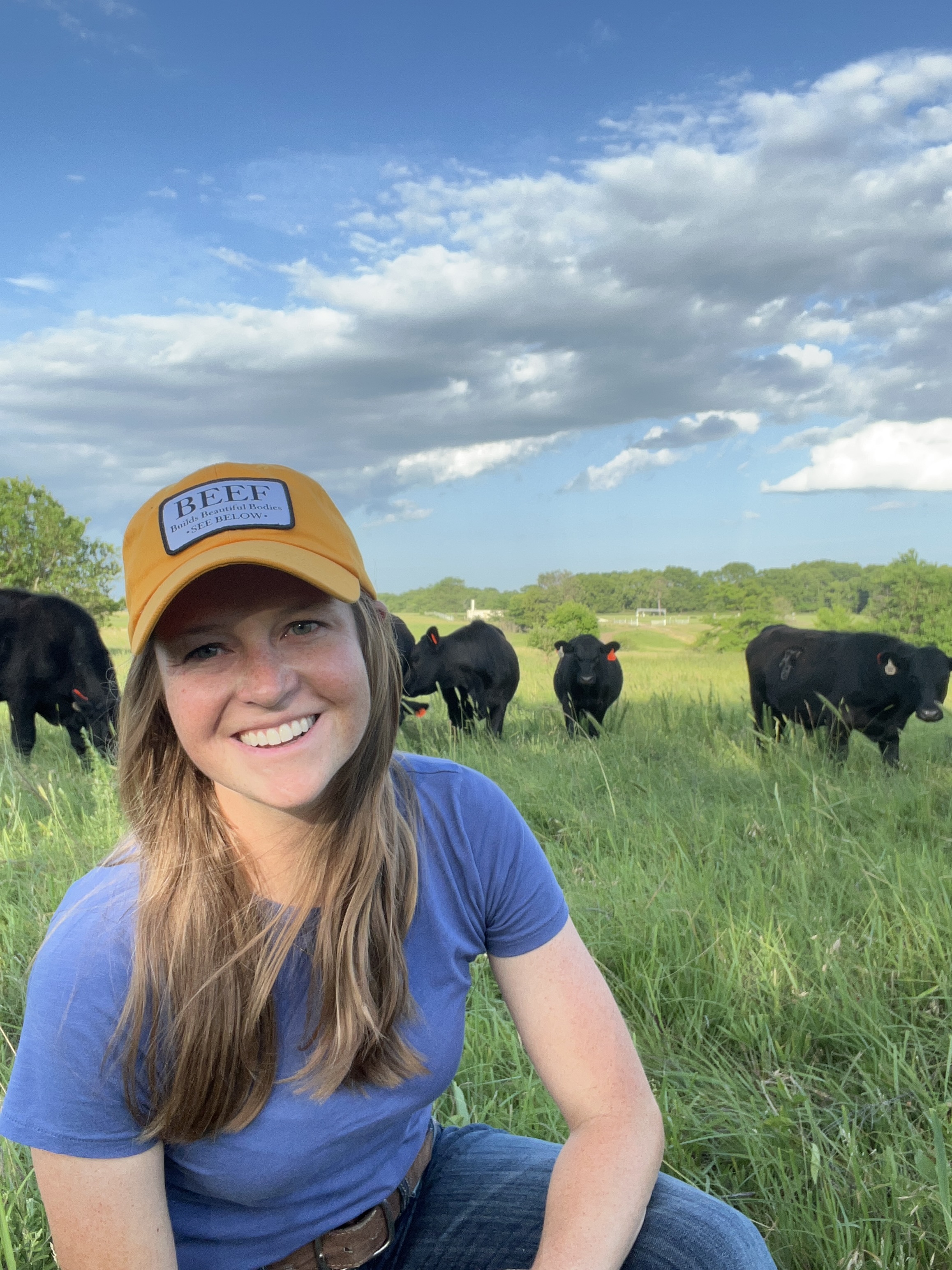 Brandi Buzzard, a Kansas rancher in a pasture with cows behind her.