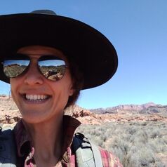 Lauren Svejcar in a big hat on a sage dominated rangeland.