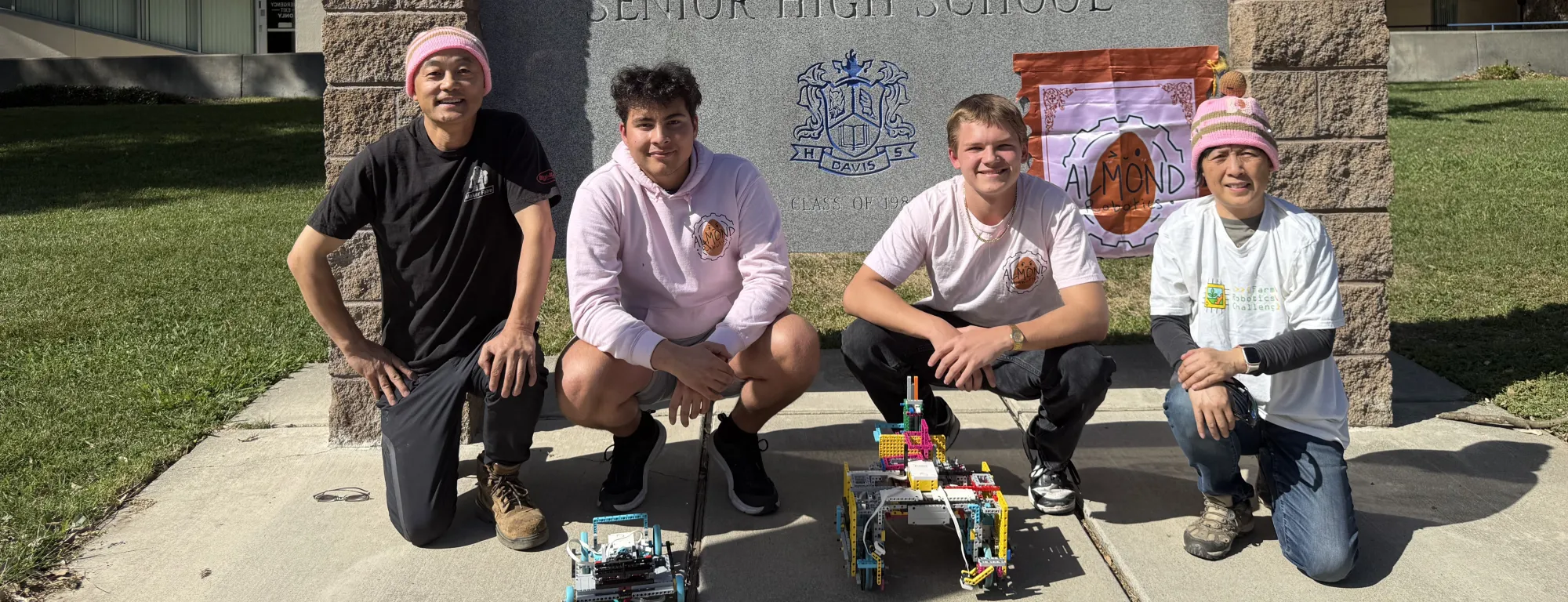 Almond Robotics, Modular Learning, Inc. team crouch by the Davis Senior High School sign