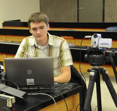 GRADUATE STUDENTS James Harwood (shown) and Amy Morice, who study with major professor James Carey of the UC Davis Department of Entomology, devote their lunch hours to Webcasting the departmental seminars. Here Harwood readies the equipment prior to a seminar. (Photo by Kathy Keatley Garvey)