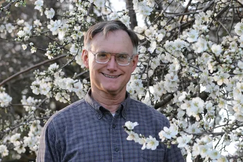 APICULTURIST ERIC MUSSEN stands amid the almond blossoms at the Harry H. Laidlaw Jr. Honey Bee Research Facility at UC Davis. He is the 2010 winner of the statewide Pedro Ilic Outstanding Agriculture Educator. (Photo by Kathy Keatley Garvey)