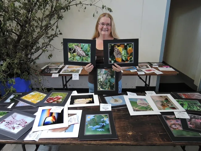 Dixon May Fair Youth Building superintendent Sharon Payne with some of the insect photographs taken by youth exhibitors.(Photo by Kathy Keatley Garvey)