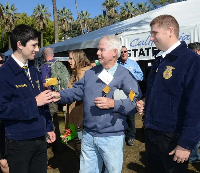 "Have something sweet from the California State Beekeepers' Association," said beekeeper Bill Cervenka at the California Ag Day celebration March 16 on the state capitol grounds. Here he hands honey sticks to Woodland FFA members Travis Tabarez (far left) and Alex Butterfield. Tabarez will be joining the Marines in June, and Butterfield, the Navy in September. Cervenka congratulated them on serving their country and said "be safe." (Photo by Kathy Keatley Garvey)