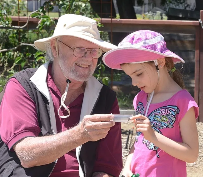 Native pollinator specialist Robbin Thorp, distinguished emeritus professor of entomology, shows a bee to haven visitor Lalibella Eaves, 6, of Quebec City, Canada. Her mother, Valerie Fournier, received her doctorate in entomology from UC Davis in 2003 and is now a professor at Laval University, Quebec City. (Photo by Kathy Keatley Garvey)
