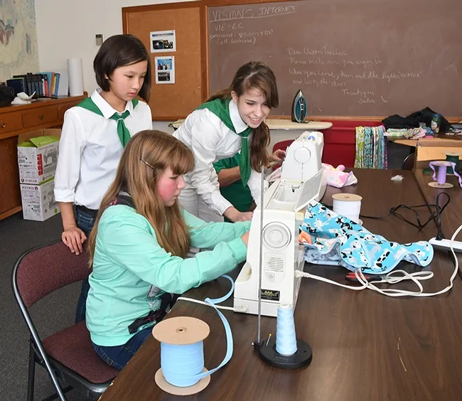 Junior 4-H leader Erica Lull (right, in the back) of the "Cuddle Me Close" project oversees the work of Suisun Valley 4-H Club member Clairese Wright (seated) while Kate Frenkel, also of Suisun Valley 4-H, watches.