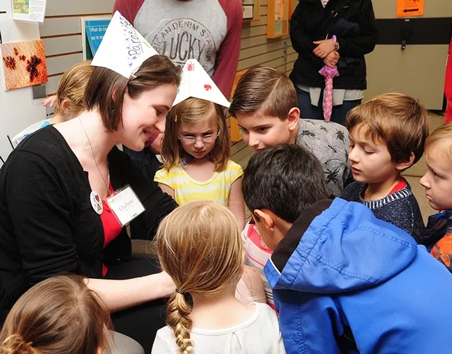 Bohart Museum visitors crowd around Charlotte Herbert, a graduate student in entomology at UC Davis, as she participates in a bed bug-feeding demonstration. (Photo by Kathy Keatley Garvey)