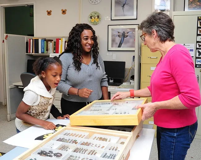 Lynn Kimsey (right), director of the Bohart Museum of Entomology, shows insect specimens to Amiyah Robinson, 8, and her mother, Chelsy Robinson, who works for Human Resources. (Photo by Kathy Keatley Garvey)