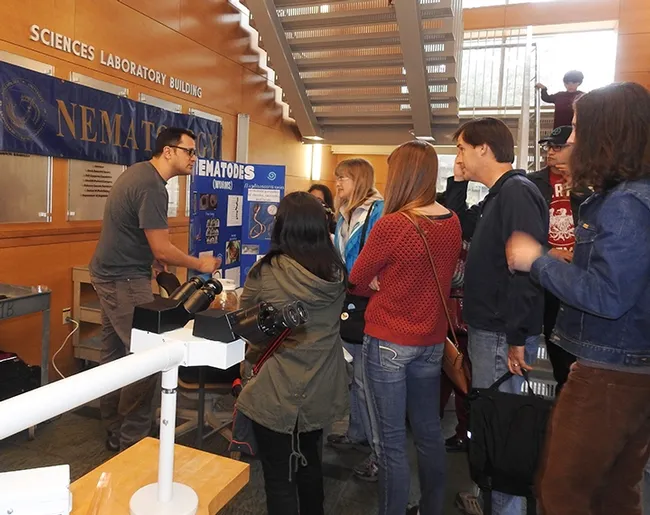 Graduate student and nematologist Christopher Pagan (far left) talks to visitors at the Nematode Collection during the 2017 Biodiversity Museum Day. The collection will be in the Sciences Laboratory Building. (Photo by Kathy Keatley Garvey)