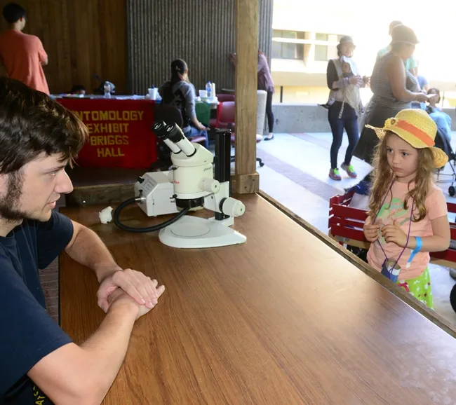 Lilliana Philips, 5, of Carmichael, listens intently as Bug Doctor Zachary Griebenow answers her question: "Do bugs get ear infections?" (Photo by Kathy Keatley Garvey)