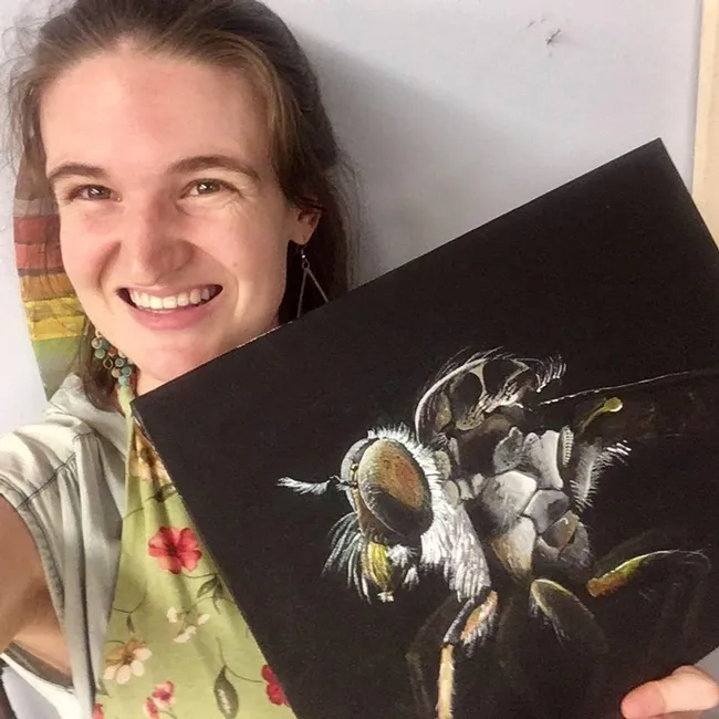UC Davis fourth-year doctoral student Charlotte Herbert Alberts holds her acrylic painting of an Assassin fly (Ommatius sp.) that she painted to celebrate World Robber Fly Day, April 30.