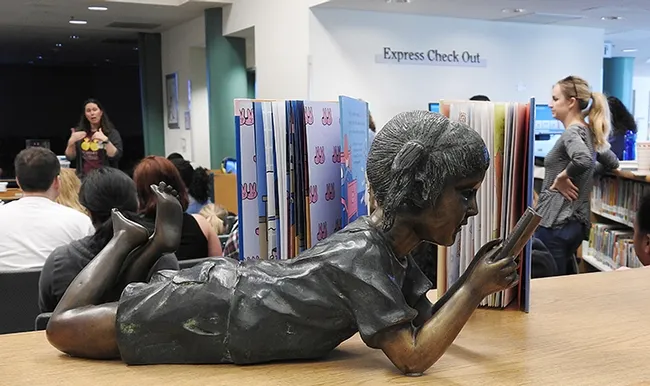 Tabatha Yang (background) of the Bohart Museum of Entomology talks about insects while the child, a sculpture, reads in the foreground at the Vacaville Public Library. (Photo by Kathy Keatley Garvey)