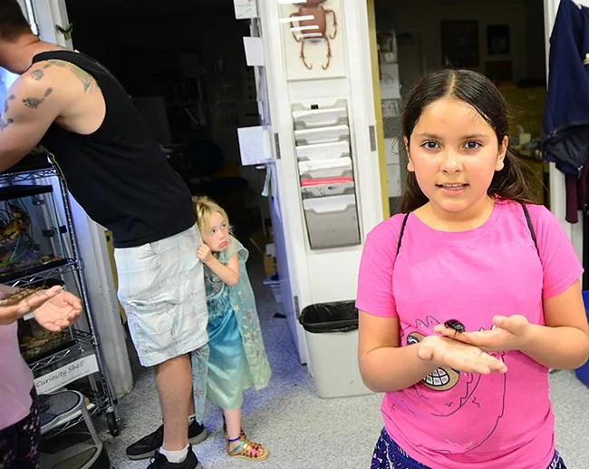 Camellia Aranda (foreground) likes a Madagascar hissing cockroach. In the background, Julianna “Ju Ju” Smith, 4, isn't so sure, as she hides behind the her father, Justin Smith of Animal Science. (Photo by Kathy Keatley Garvey)