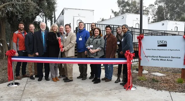 UC Davis-affiliated personnel pose with USDA personnel for a ribbon-cutting photo. From left are Charley Nye, UC Davis; Paul Pratt of USDA; Kevin Hackett of USDA; Anita Oberbauer of UC Davis; Eric Mussen of UC Davis; Robert Matteri of USDA; Neal Williams, Brian Johnson, Elina Niño and Bernardo Niño, all of UC Davis; and Julia Fine and Arathi Seshadri, USDA.