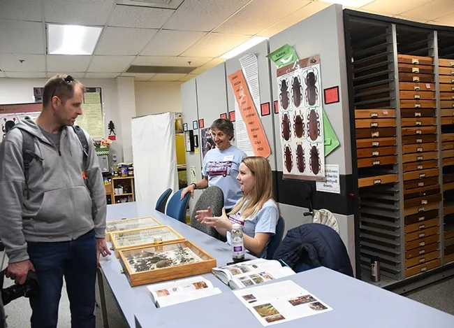 Lynn Kimsey, (standing), director of the Bohart Museum of Entomology, and Crystal Homicz, a doctoral student in forest entomology, show beetles to a visitor. (Photo by Kathy Keatley Garvey)