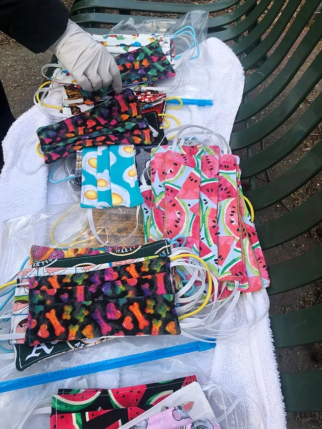 A gloved hand reaches for one of the many masks made by Teresa Hickman. (Photo by Kathy Keatley Garvey)