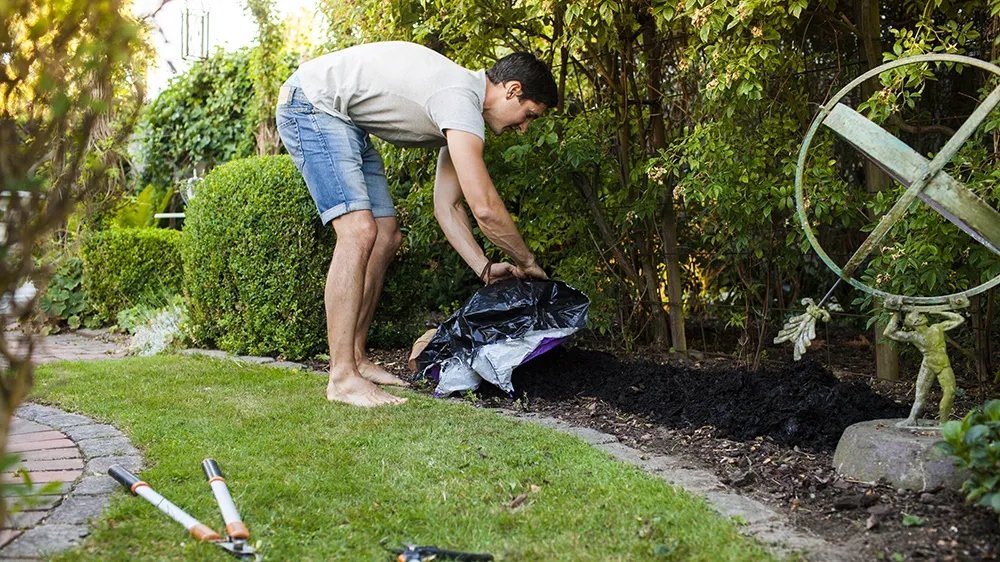 full-length-side-view-of-mature-man-spreading-fert-BTWN9UN