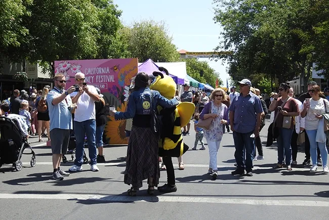May I take your photo? Of course, you may! "Queen Bee" Wendy Mather, program manager of the California Master Beekeeper Program, poses with a festival-goer. (Photo by Kathy Keatley Garvey)