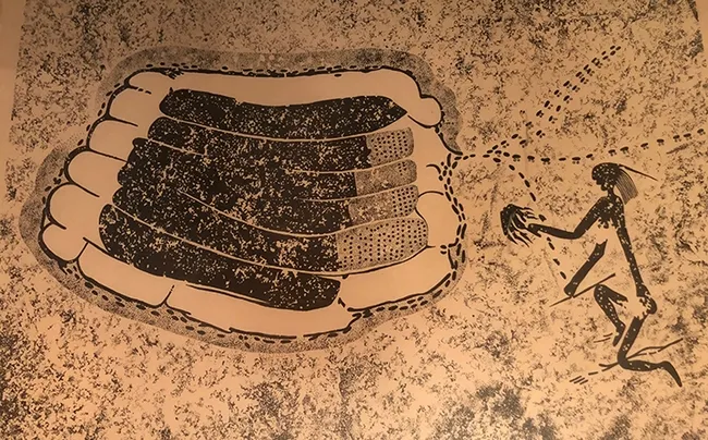 This framed photo of an image, once belonging to the late Extension apiculturist Eric Mussen, shows an ancient rock painting from Zimbabwe. A beekeeper is using a smoker.