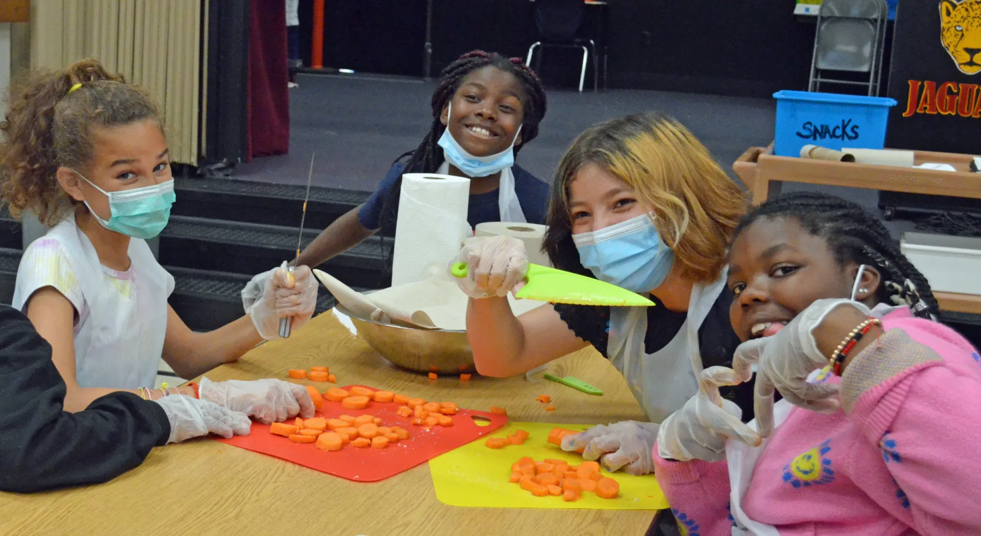Cooking Academy students cutting up carrots and posing for the camera