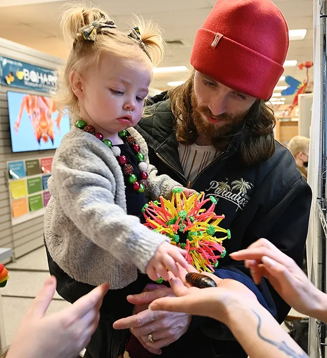 Chris Marlatte watches as his daughter, Reagan, a year and a half, pets a Madagascar hissing cockroach. (Photo by Kathy Keatley Garvey)
