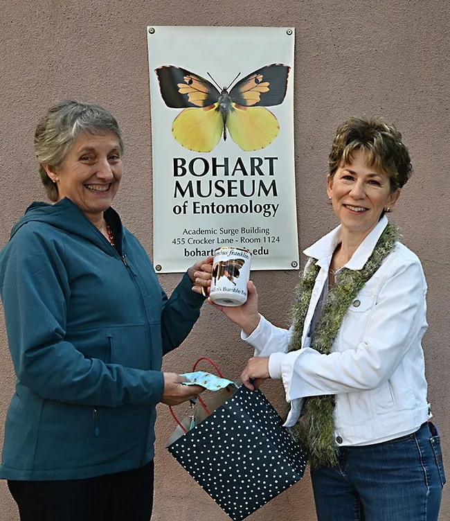 Lynn Kimsey (left), director of the Bohart Museum of Entomology, presents a prized coffee cup with an image of Franklin's bumble bee to Ria de Grassi. (Photo by Kathy Keatley Garvey)