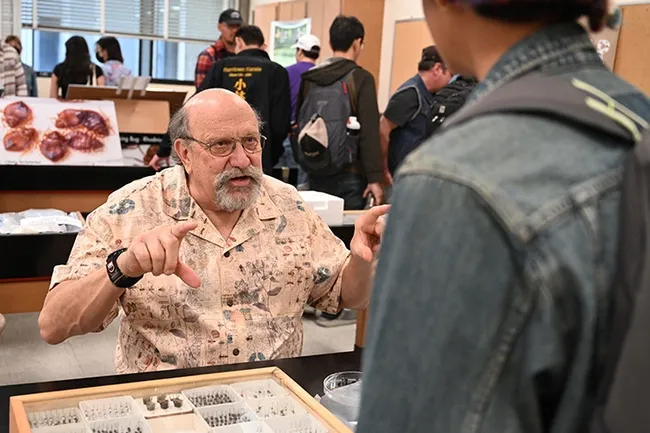 UC Davis forensic entomologist Robert "Bob" Kimsey explains his research. In back is a graphic of bed bugs. (Photo by Kathy Keatley Garvey)