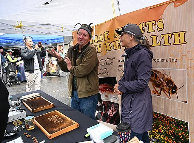 Wendy Mather, co-program manager of the California Master Beekeeper Program (CAMBP) and CAMBP apprentice level Rick Moehrke of Vacaville discuss the merits of beekeeping with festival attendees. Moehrke became a beekeeper last September. (Photo by Kathy Keatley Garvey)