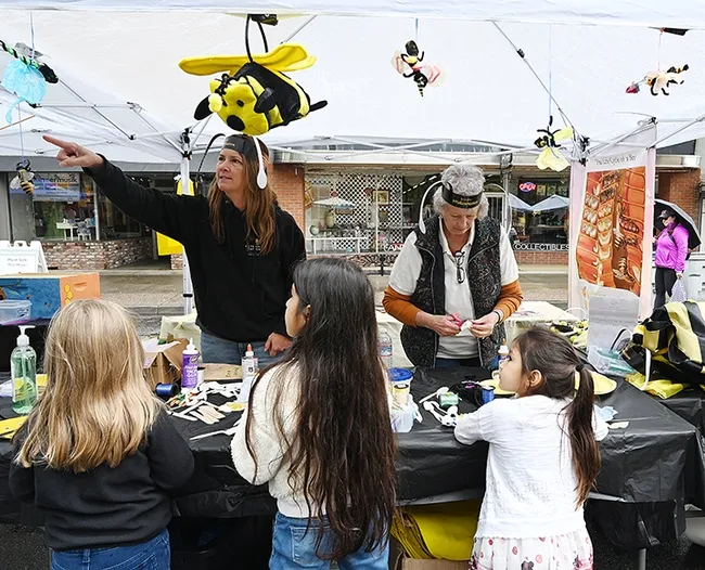 CAMBP master beekeeper Sara Cutrignelli of San Martin explains bee behavior to youngsters at the arts and crafts booth, while fellow CAMBP member Paula Brackett, an apprentice level beekeeper, helps youngsters with their creative ideas. (Photo by Kathy Keatley Garvey)