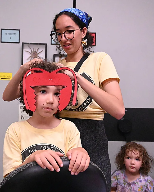 UC Davis senior entomology major Morgan Myrhe adjusts the ant headgear on her son, Galileo, 5, while her daughter, Esmeralda, 2, watches. (Photo by Kathy Keatley Garvey)