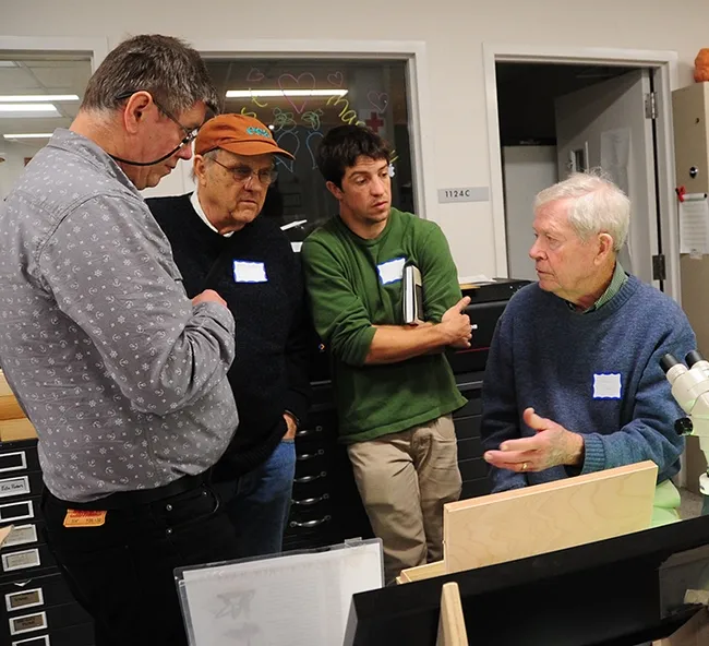 In this 2017 archived photo, Jerry Powell (seated at microscope) talks to colleagues at a Lepidopterist Society meeting at the Bohart Museum of Entomology. From left are entomologist Max Klepikov of Berkeley; UC Davis distinguished professor Don Strong of the Department of Evolution and Ecology; and Eric Lopresti, then a UC Davis graduate student. (Photo by Kathy Keatley Garvey)