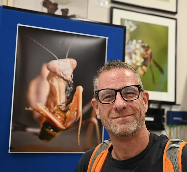 Talented photographer Ian Alexander Levin of Sacramento displayed enlarged images of praying mantises at the Bohart Museum of Entomology. Behind him is one of his images of a mantis eating a bee. Levin owns a child daycare in Sacramento and likes to share his images and critters with the youngsters in a "Critter Corner." He is the administrator of the Facebook page, SacraMantis. (Photo by Kathy Keatley Garvey)