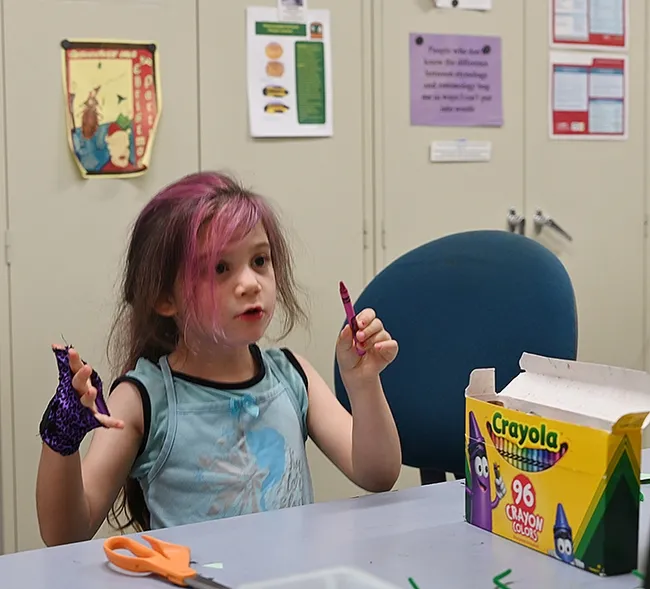 Soraya Qaqunah, 4, of Davis considers what crayons to use to make her "Mantis on a Stick." (Photo by Kathy Keatley Garvey)