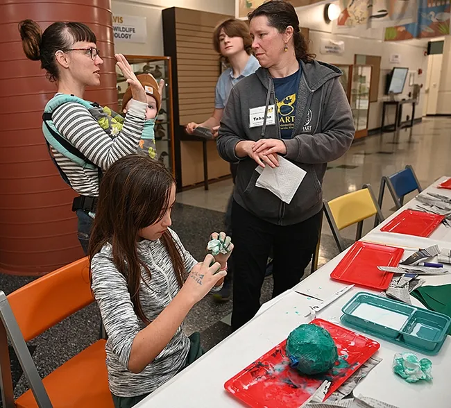Skylan Potter, 11, of Sacramento works on creating a wasp nest at the Bohart Museum of Entomology open house. In back are her mother, Camille Potter, and baby brother, Kehlan Kaufeldt, age 1; Tabatha Yang, Bohart education and outreach coordinator and Bohart associate Andrew Logan, who staffed the table. (Photo by Kathy Keatley Garvey)