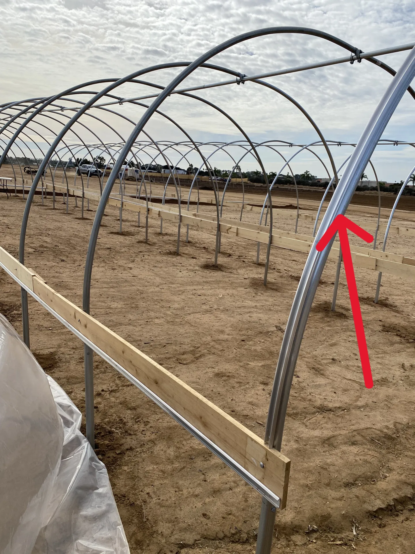 Figure 7. Lock channels, indicated by the red arrow, were secured to the first and last hoops of each high tunnel using self-tapping screws.