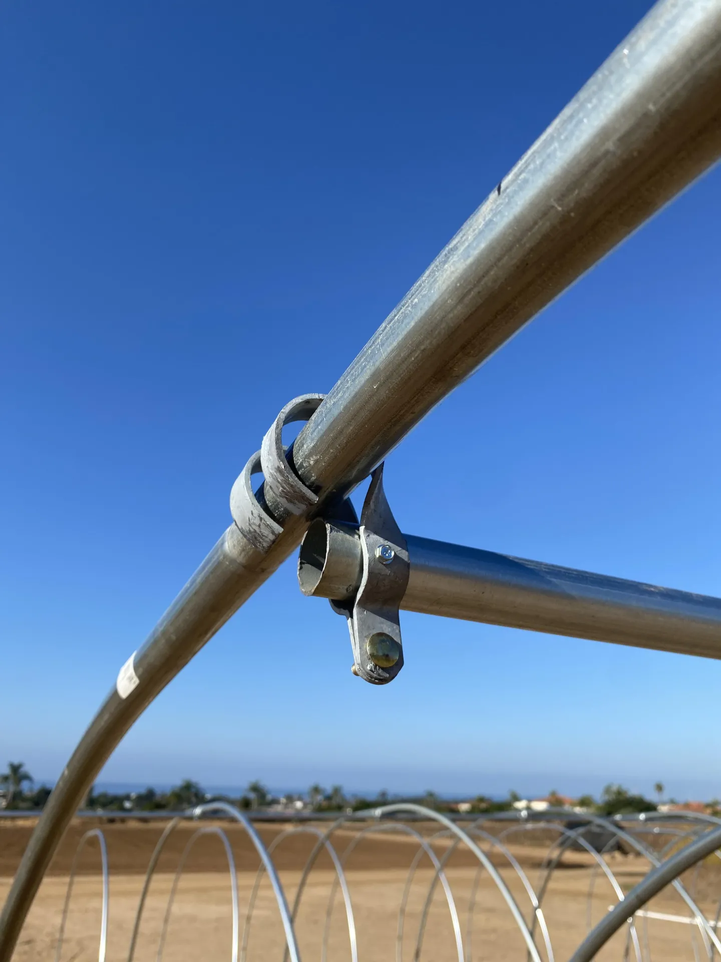 Figure 4. The end connector will be placed so the loops are going towards the outside of the high tunnel and the ridgepole is being held in place insi