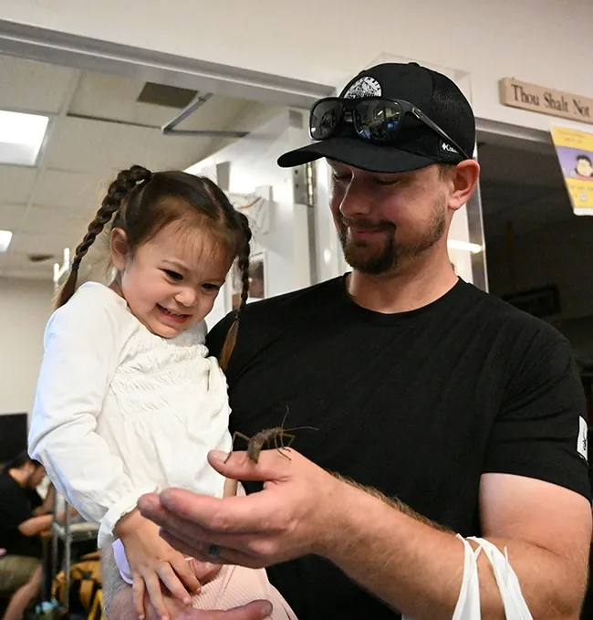 Three-year-old Everly Puckett checks out a stick insect held by her father, Ryan Puckett, a UC Davis employee. (Photo by Kathy Keatley Garvey)
