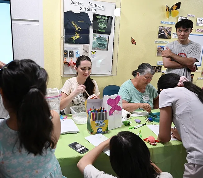 UC Davis graduate student (forensics) Riley Hoffman and fellow Bohart volunteer Barbara Heinsch lead a family arts and crafts activity. (Photo by Kathy Keatley Garvey)