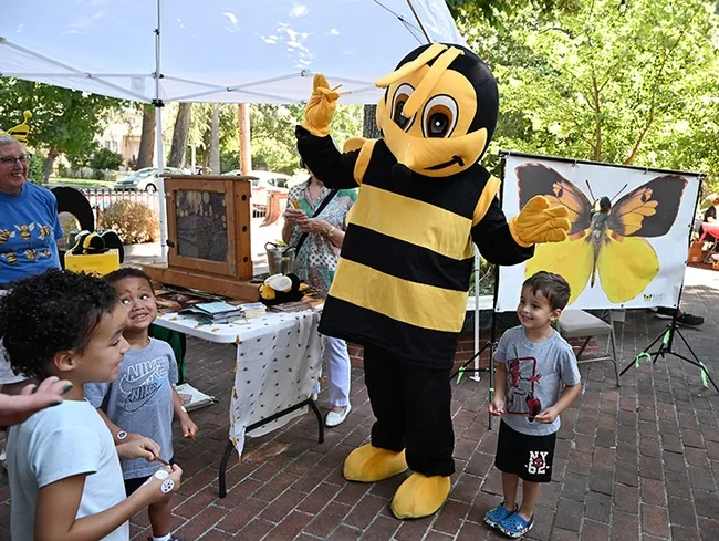 Children expressed excitement as they circled The Honey Bee. In the back is a cutout banner of a California dogface butterfly, the state insect, from the Bohart Museum of Entomology. (Photo by Kathy Keatley Garvey)
