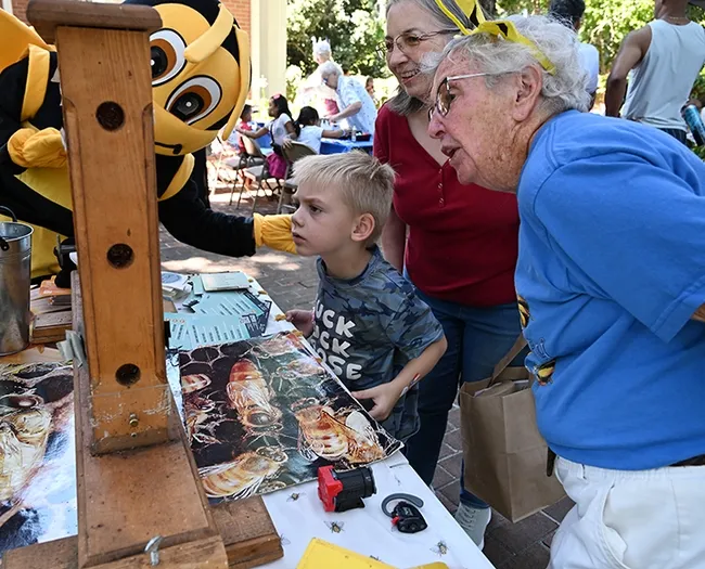 Honey Bee (Dr.George Stock, a retired physician) peeks around to see what's happening by the bee observation hive. Beekeeper Ettmarie Peterson (right) is chatting with Hunter Banks, 3, and his grandmother, Margaret Banks. Hunter is wearing his "Buck, Buck, Moose" t-shirt. (Photo by Kathy Keatley Garvey)