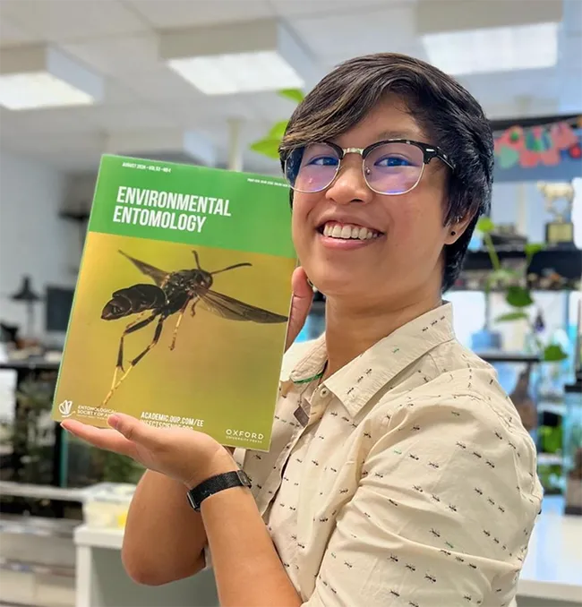 RJ Millena, a doctoral candidate of comparative biology in the lab of Professor Jessica Ware, American Museum of Natural History (AMNH) holds a copy of the journal "Environmental Entomology." Her research is the cover story. (Photo by UC Davis alumnus Lohit Garikipati, now a doctoral student at AMNH)