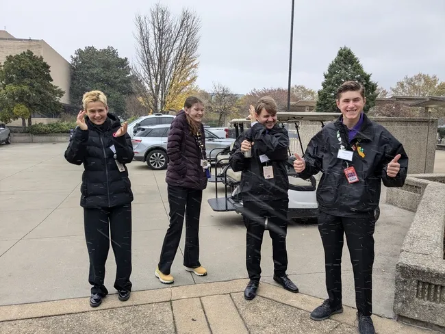 4 youth outside in heavy jackets, wincing from the cold.