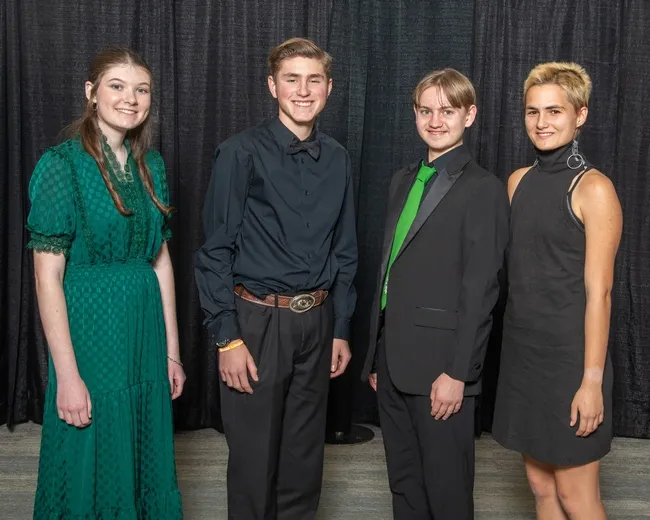 4 youth in dress clothes in front of black curtain