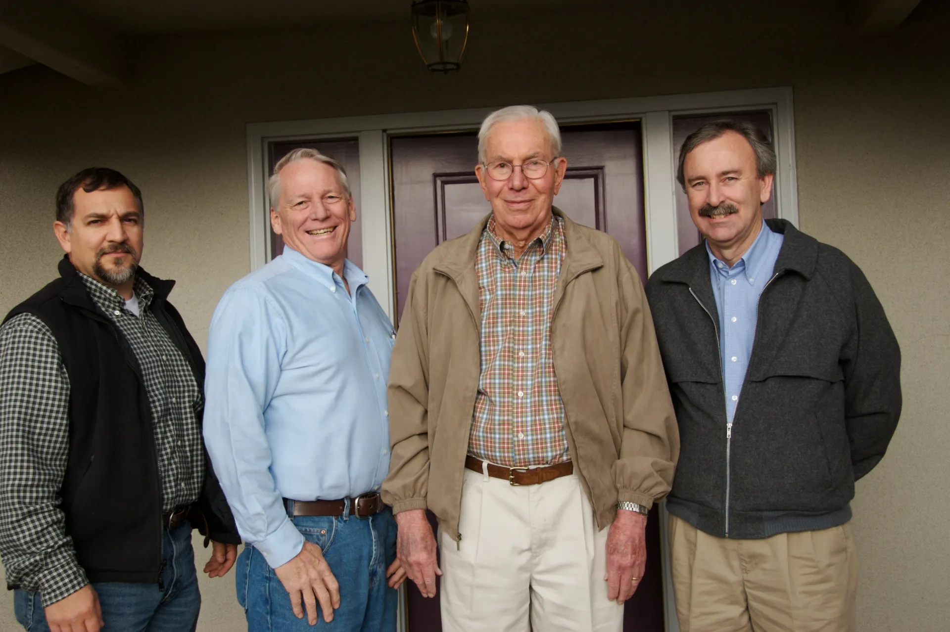 Four men standing on a front porch