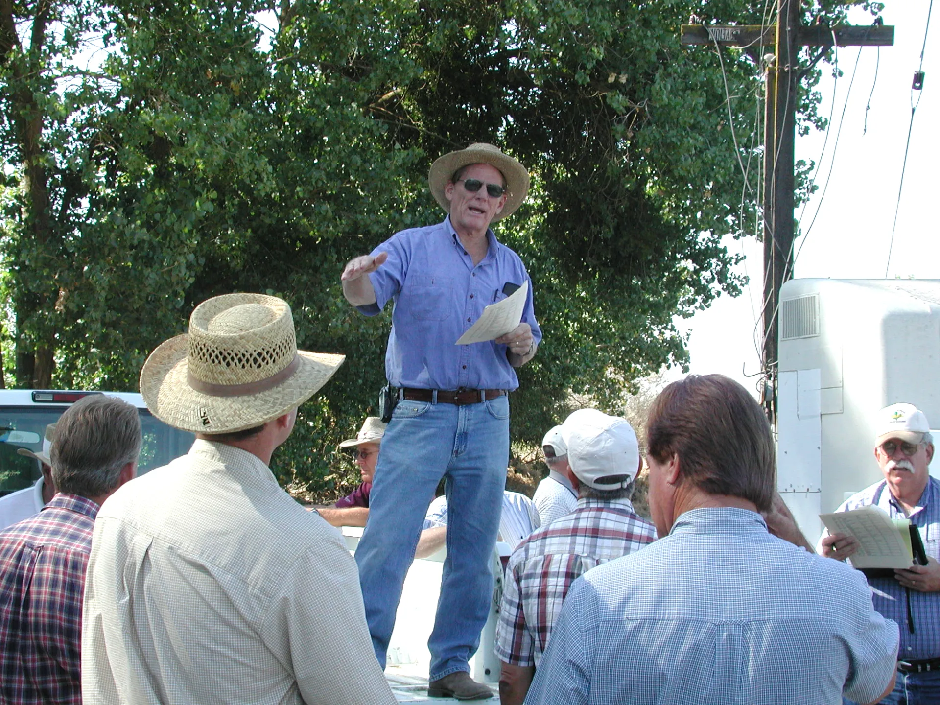 Leavitt standing on a truck speaking to a group of farmers at a field day