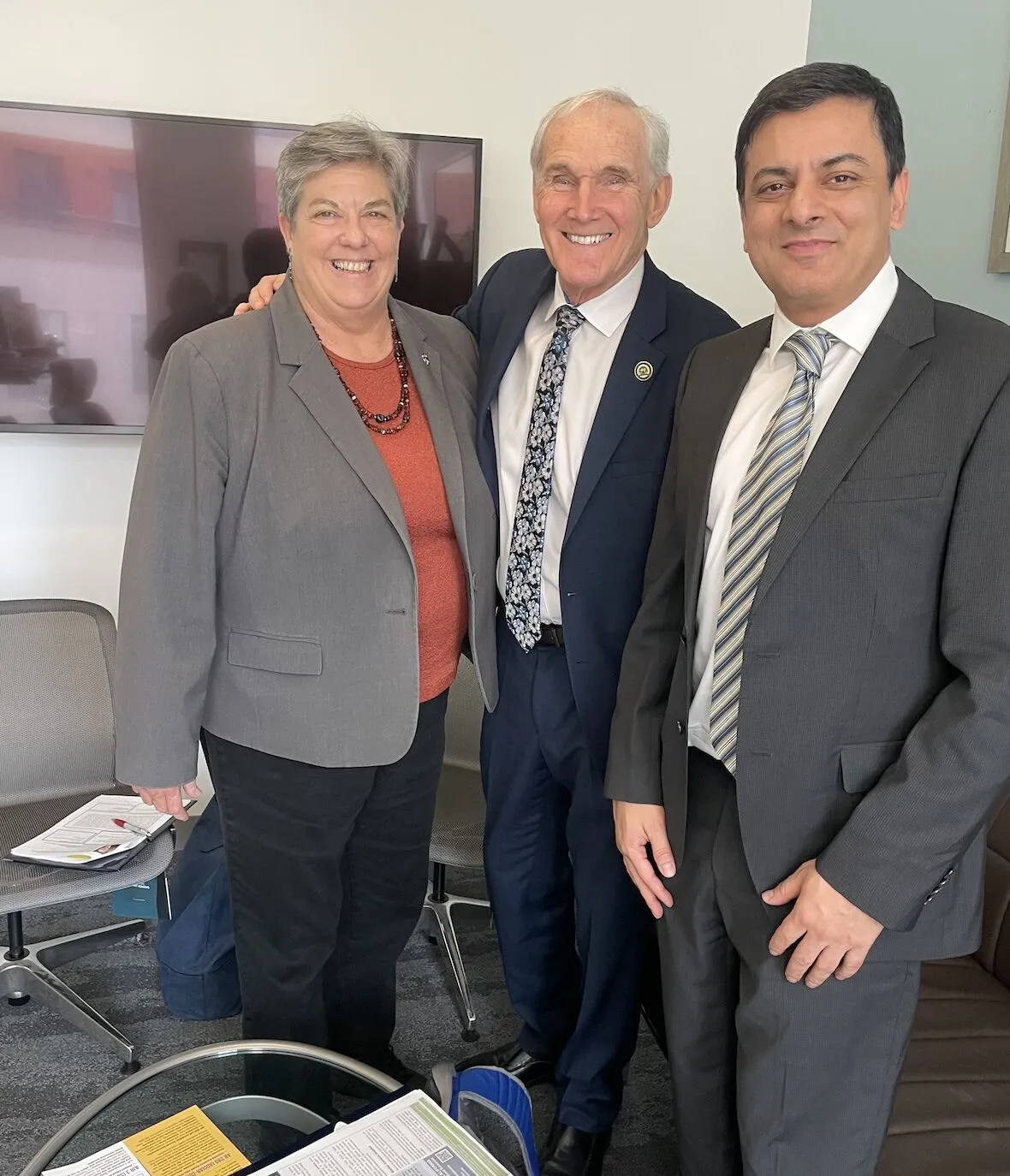 Three people stand in an office