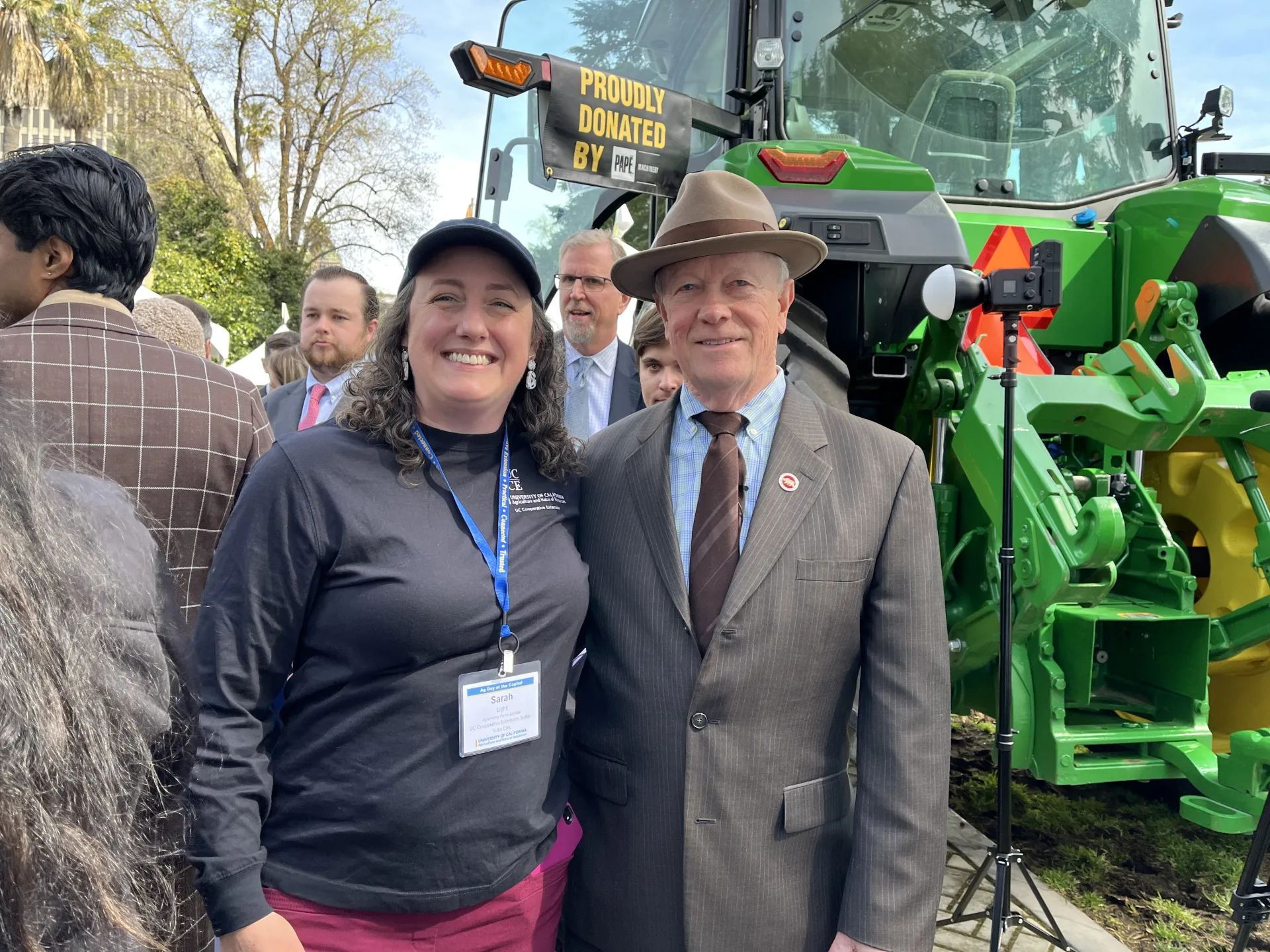 Sarah poses beside the senator in front of a green tractor