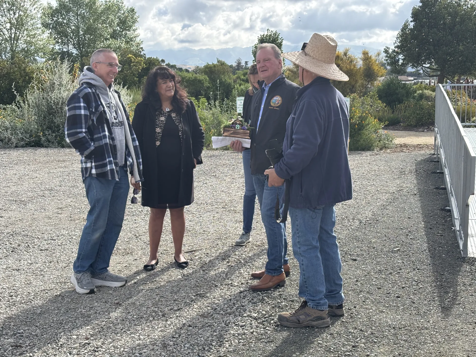 State Senator Dave Cortese speaks with four people while standing in a garden.