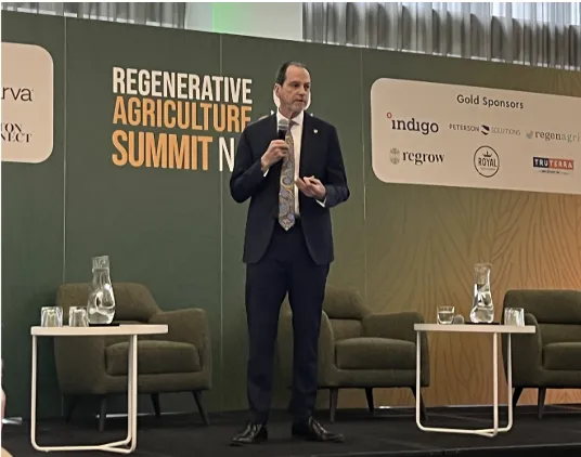 Honeycutt speaks in front of a Regenerative Agriculture Summit, North America backdrop.