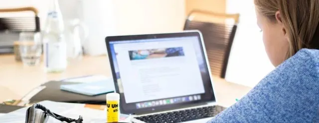 Employee working on a laptop at a table.